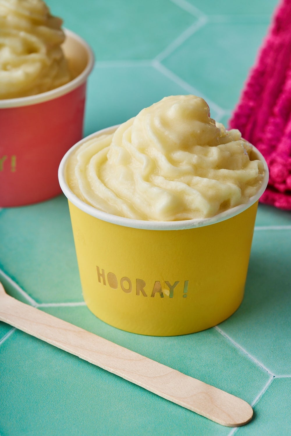 Soft smooth Dole Whip served in yellow and red paper cups.