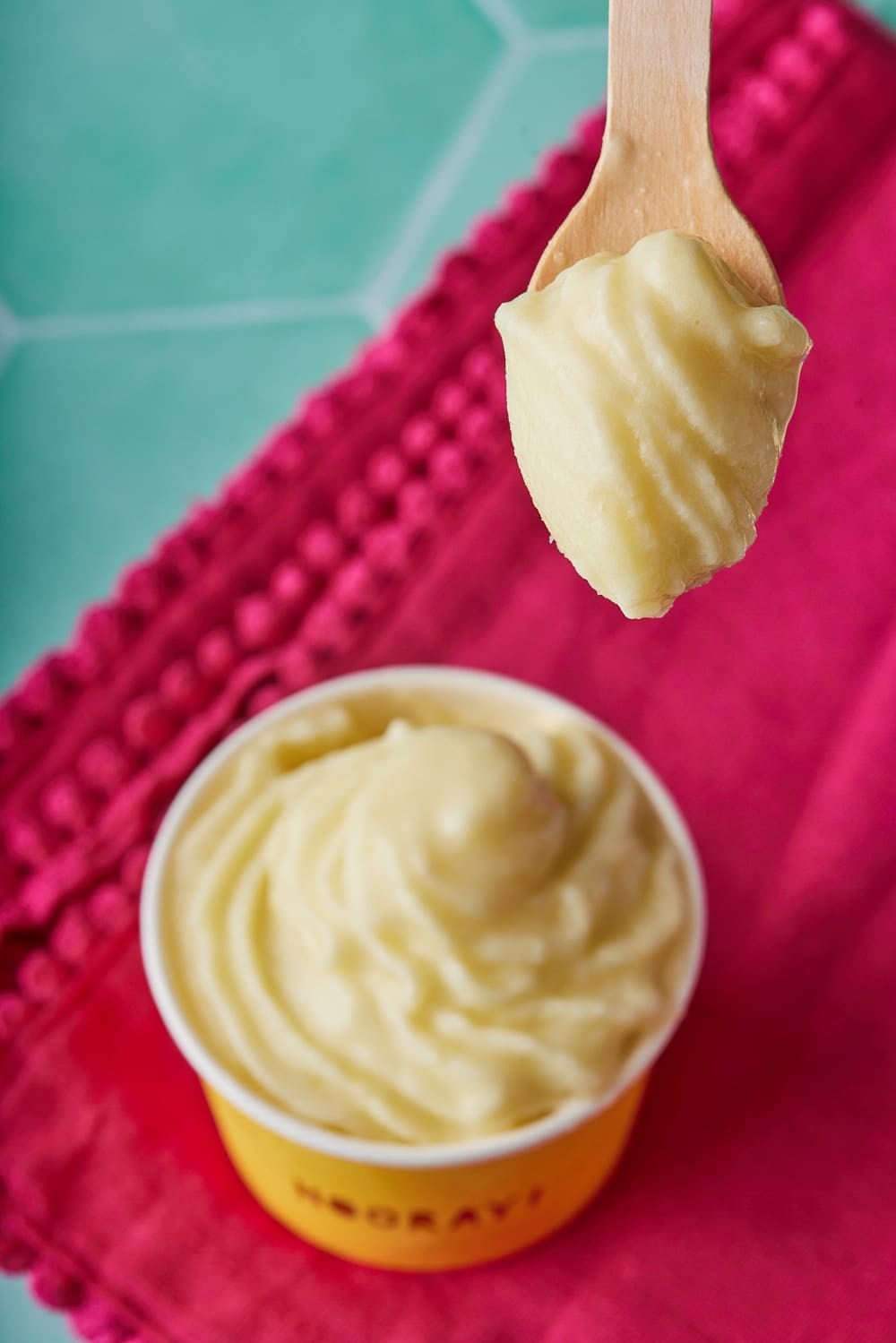 Top-down view of Dole whip served in a paper cup, with a spoonful of dole whip above it.