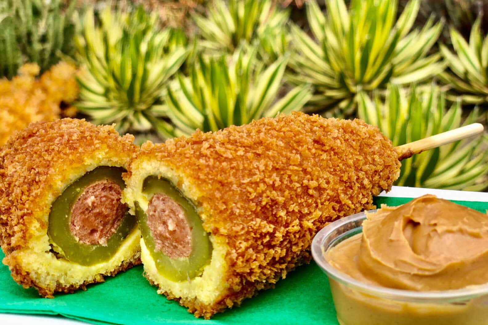 A fried pickle corn dog next to peanut butter.