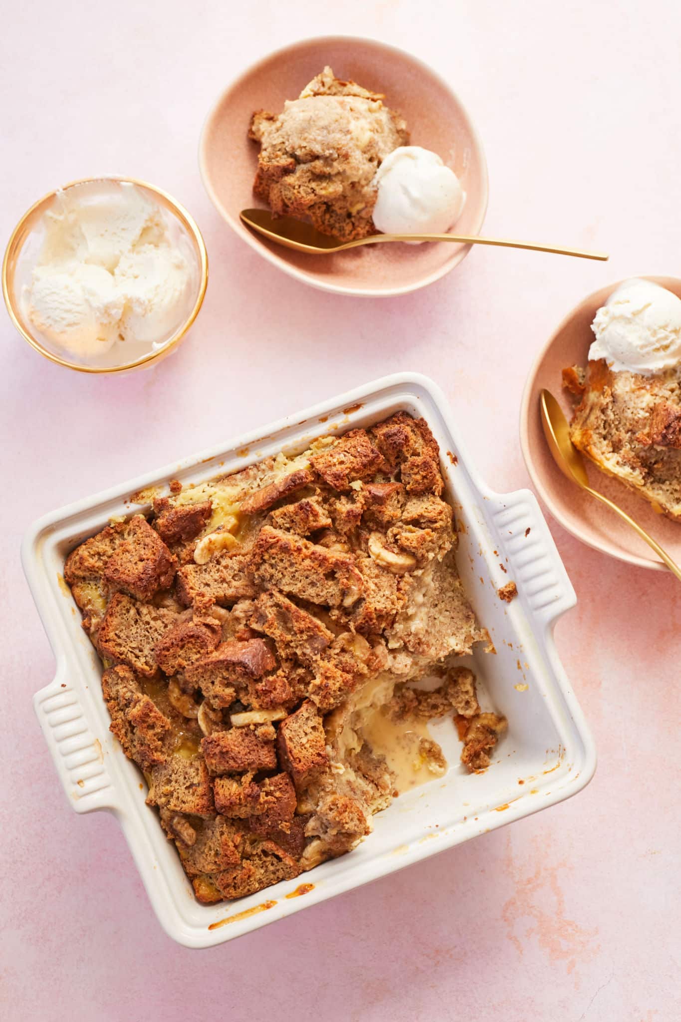 Banana Bread Pudding in a white dish next to bowls with servings.