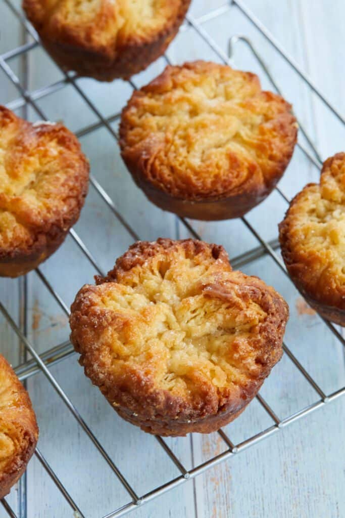 Kouign-Amann pastries are baked golden brown with buttery, flaky texture, topped with sprinkled sugar