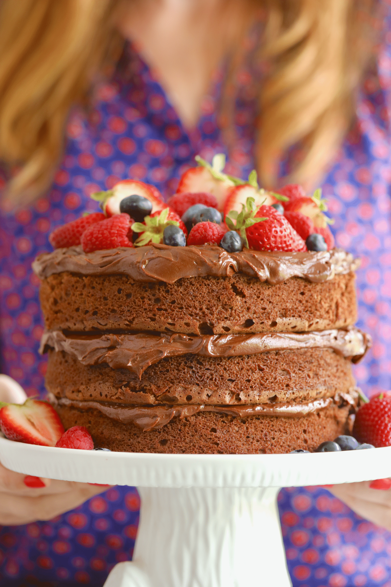 A three-layer Microwave Chocolate Cake with frosting between layers and fresh berries on top. 