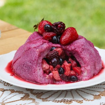 A summing berry pudding cake topped with fresh berries.