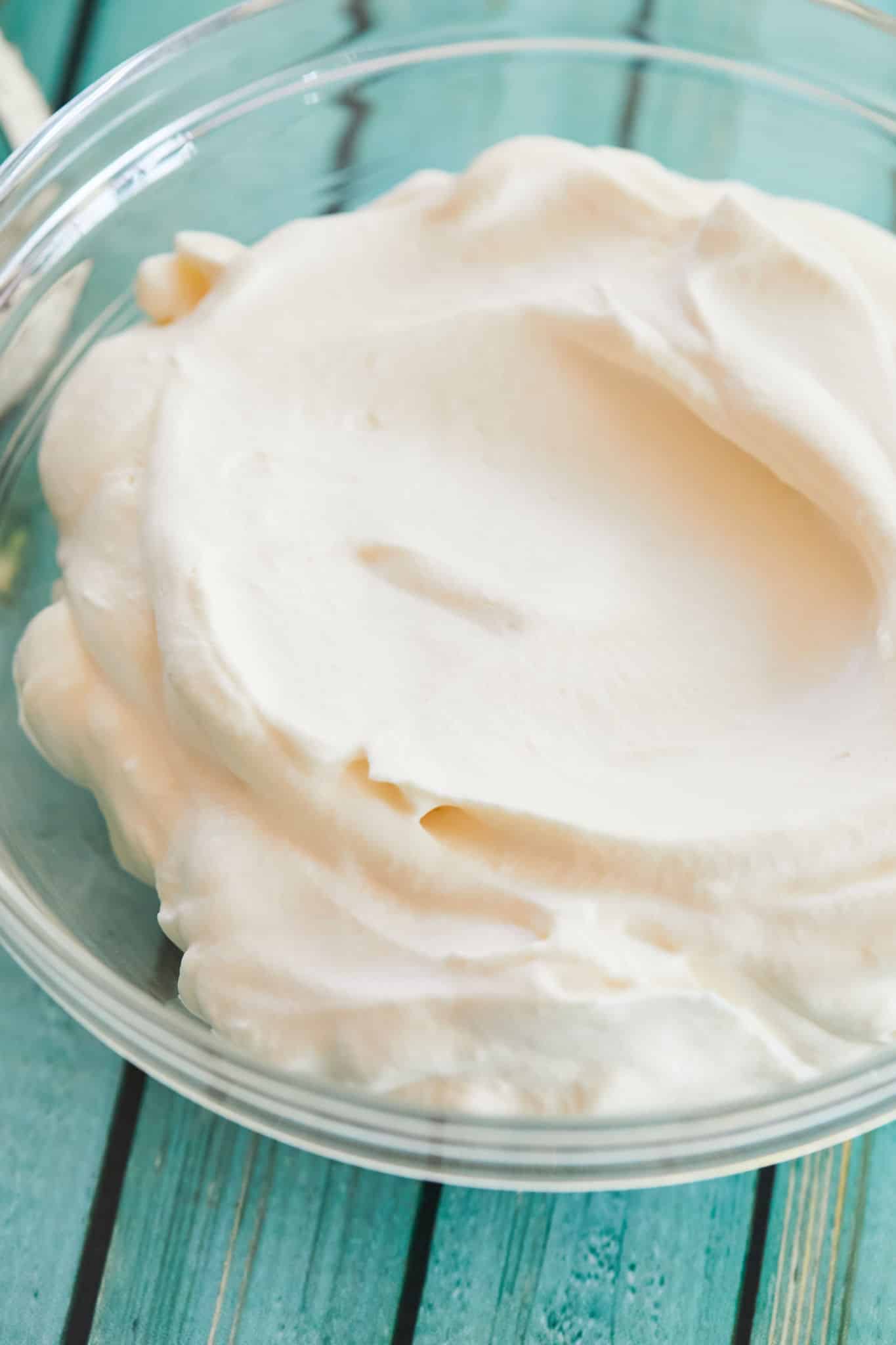 Creamy, white stabilized whipped cream sits in a clear bowl.