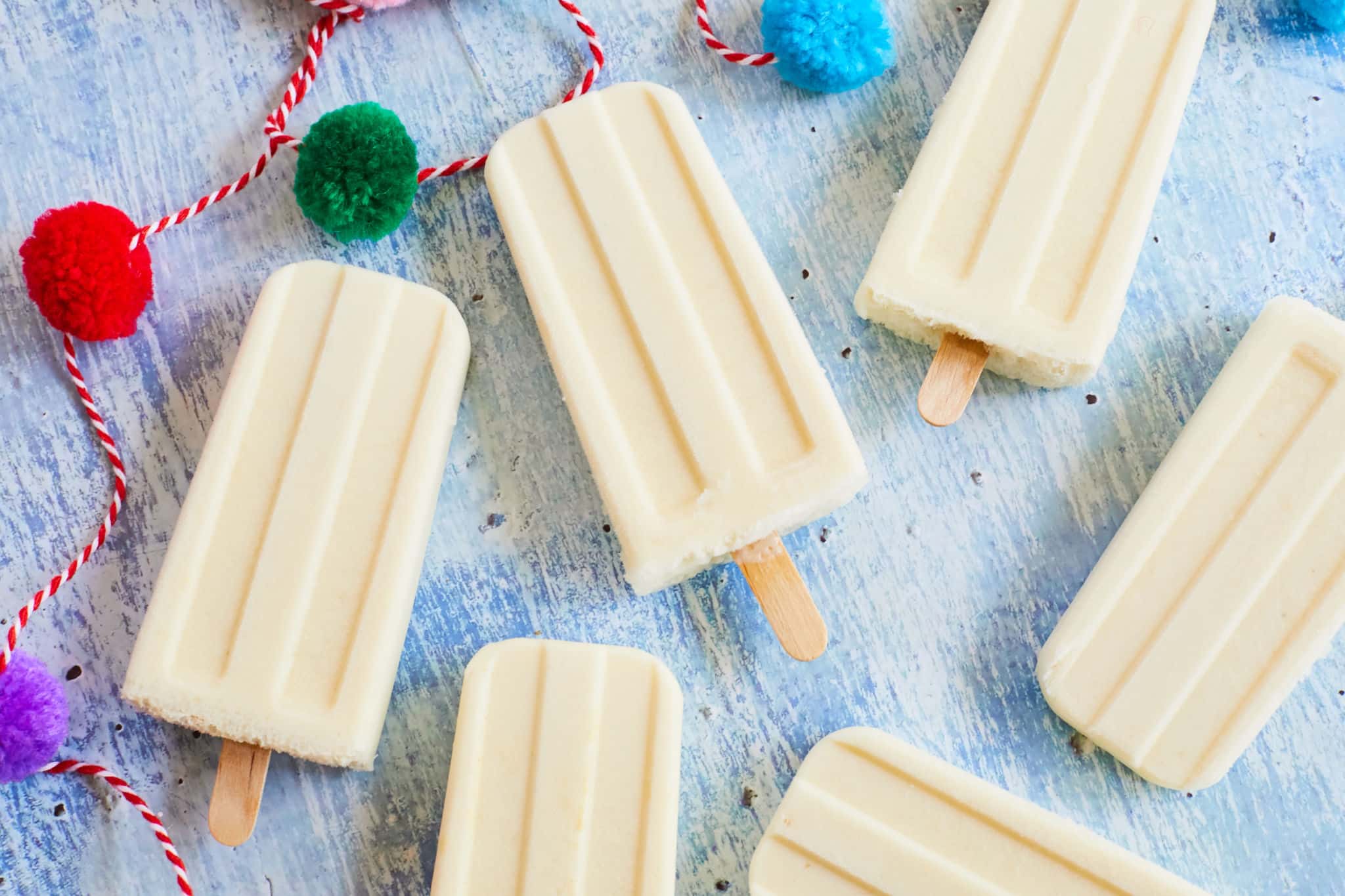 Piña colada popsicles laying flat on a table.