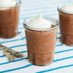 Three jars of chocolate pudding with whipped cream on top.