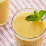 A glass of mango lassi topped with mint.