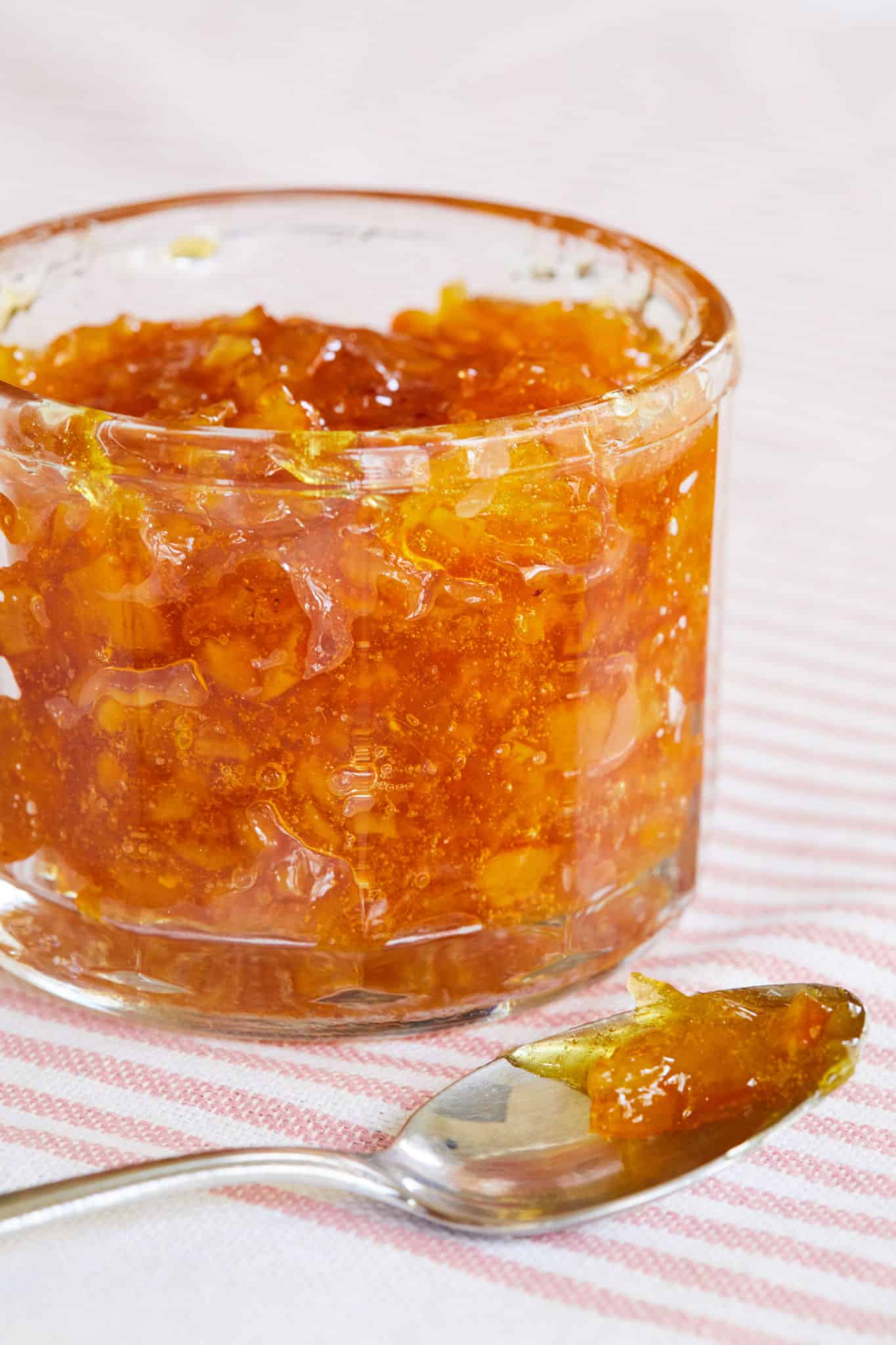 Orange Marmalade in a jar, with a spoon next to it.