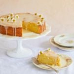 A whole orange cake with a slice removed.