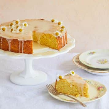 A whole orange cake with a slice removed.