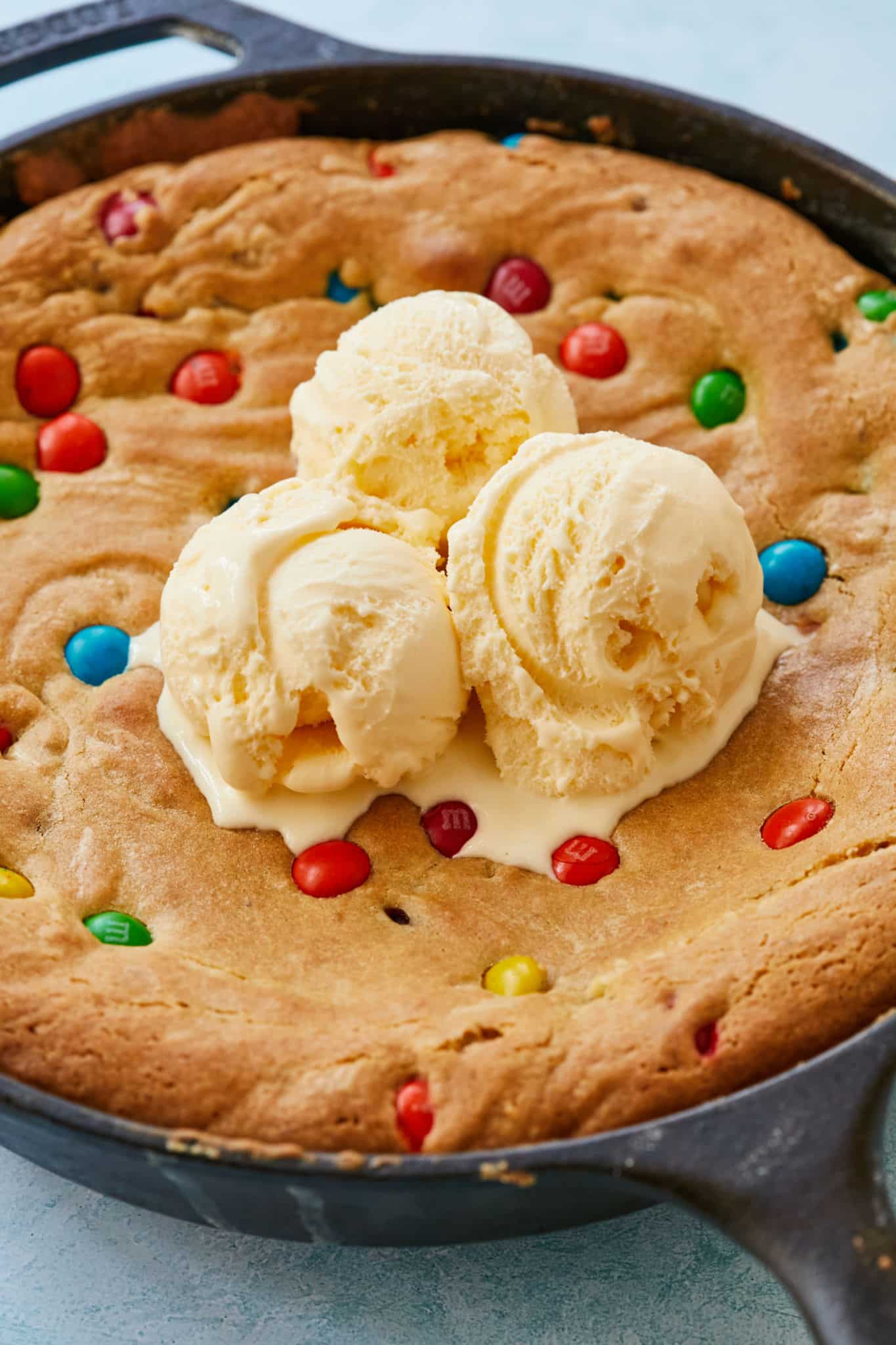A warm skillet cookie topped with vanilla ice cream.