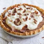 A chocolate pudding pie with golden crust, silky smooth pudding filling, softly whipped cream and chocolate shaving.