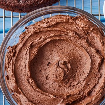 Top-down view of a bowl of smooth chocolate buttercream frosting.