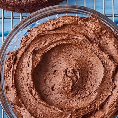 Top-down view of a bowl of smooth chocolate buttercream frosting.