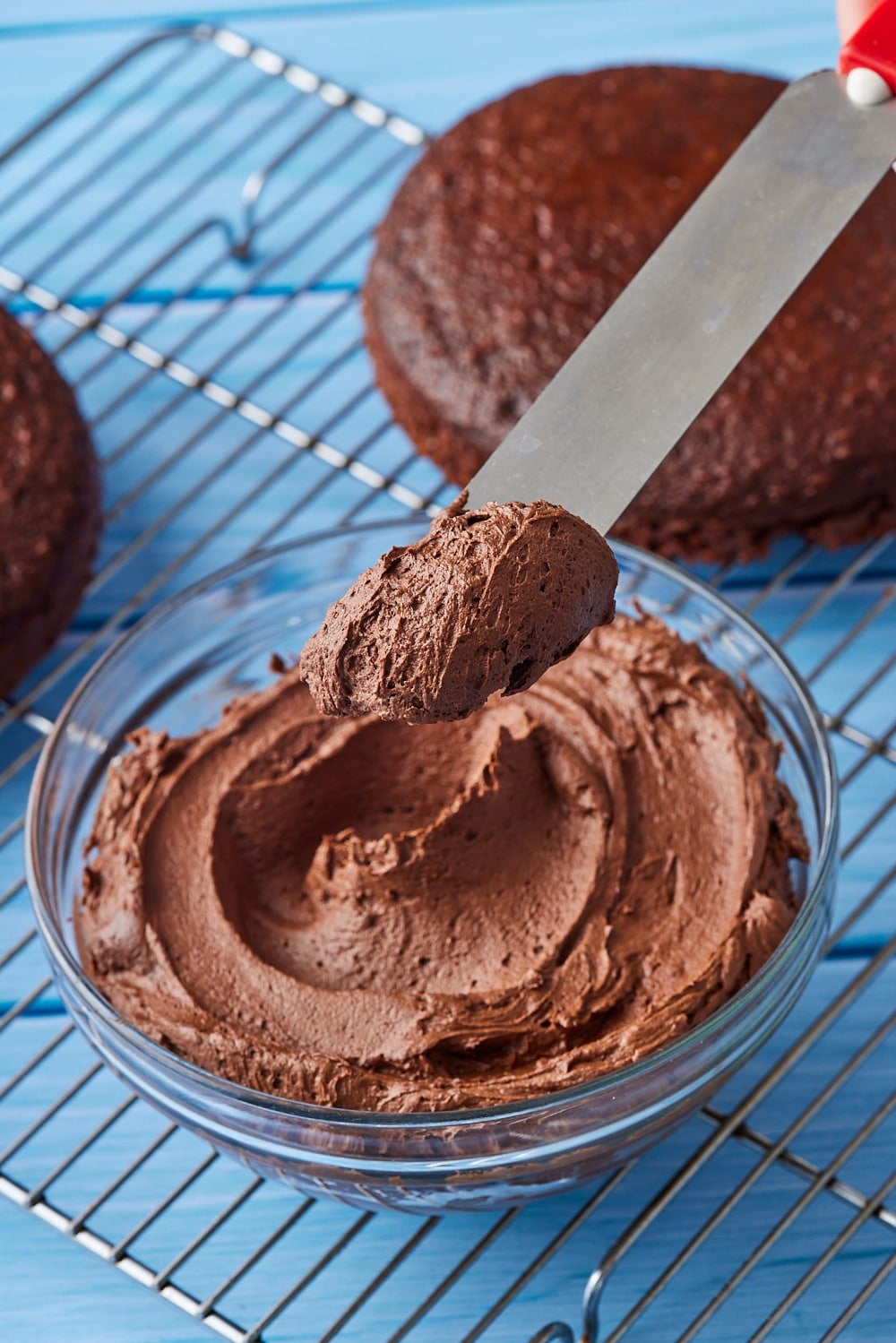 An offset spatula scooping chocolate buttercream frosting. 