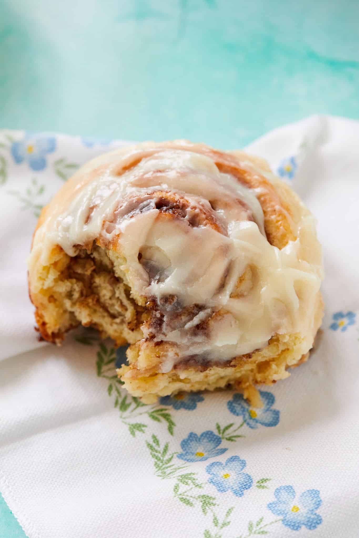 A cinnamon roll with a bite taken out of it to show the texture inside of it.