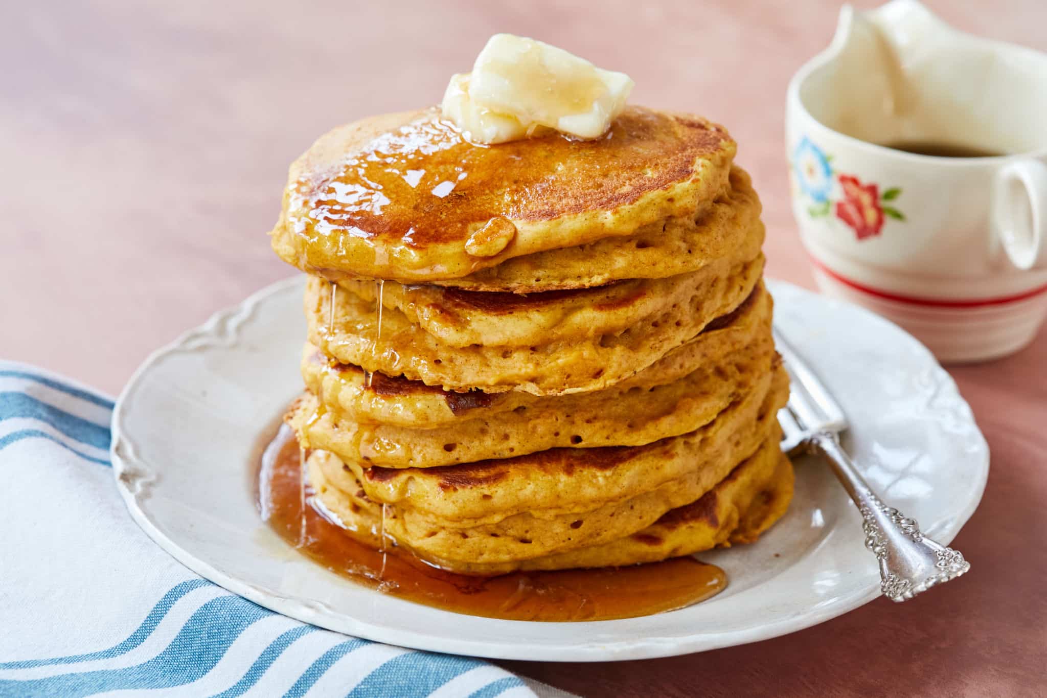 A stack of pumpkin pancakes topped with butter and syrup.