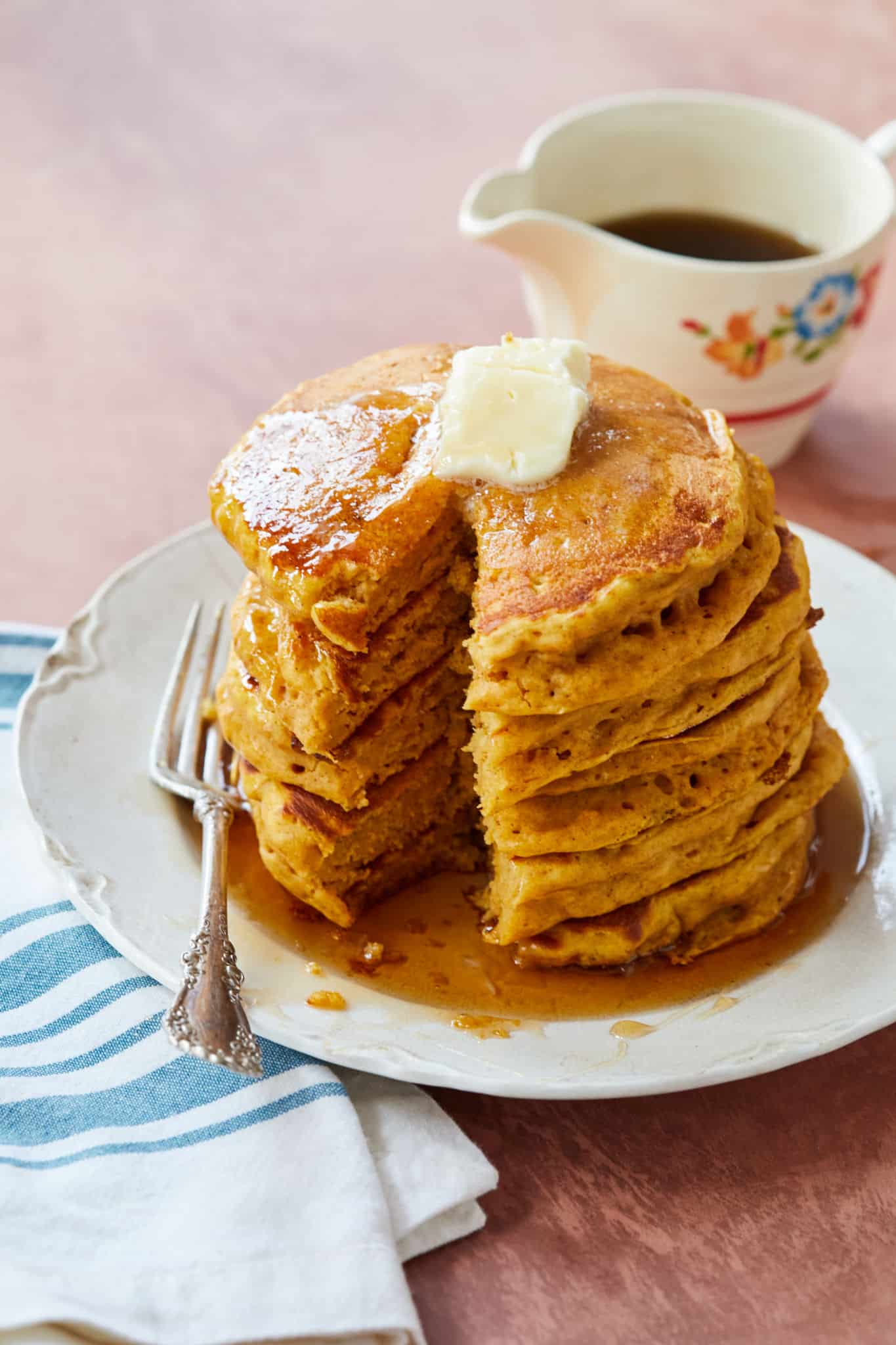 A stack of pumpkin pancakes with a slice taken out of it.