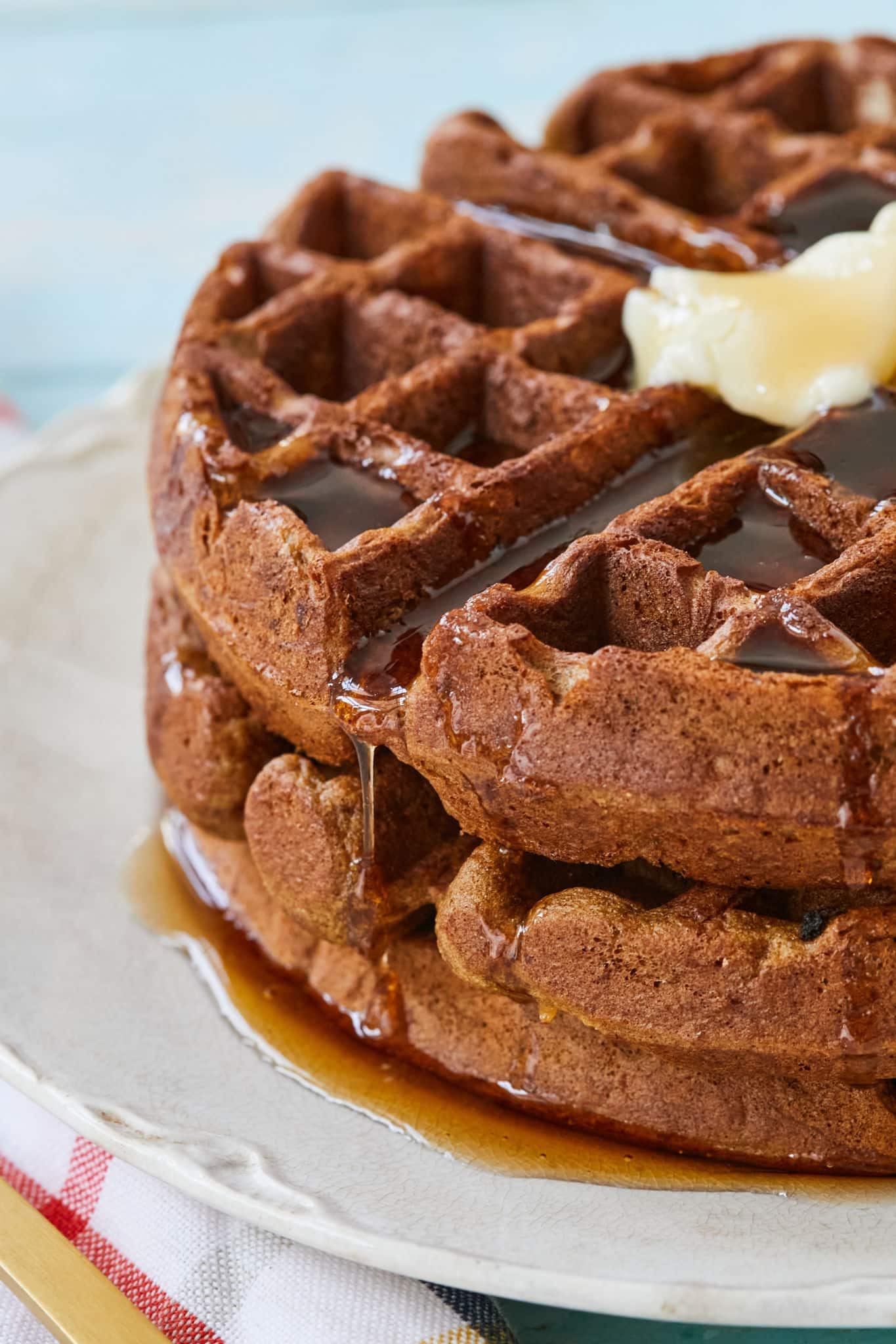 A close up of syrup dripping down gingerbread waffles.