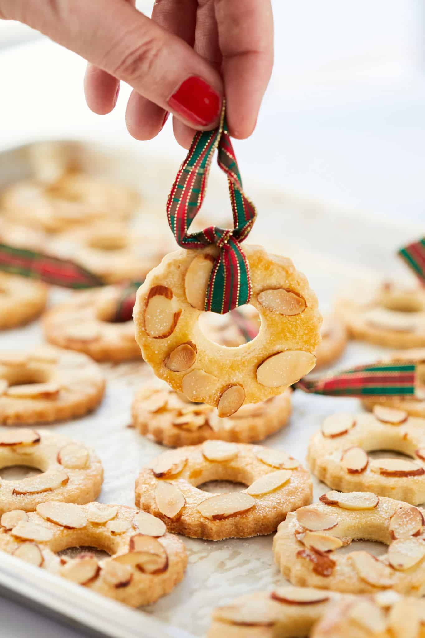 Holding a Kerstkransjes cookie by a ribbon.