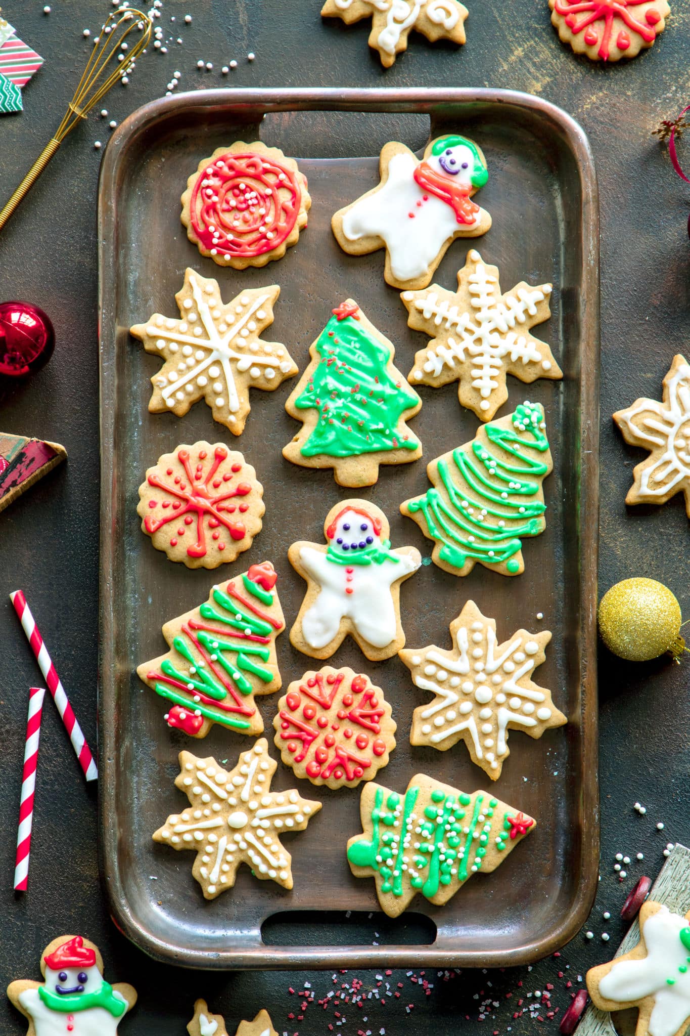 Frosted Spiced Sugar Cookies on a baking sheet. The cookies are decorated as snowmen, Christmas trees, and snowflakes. 