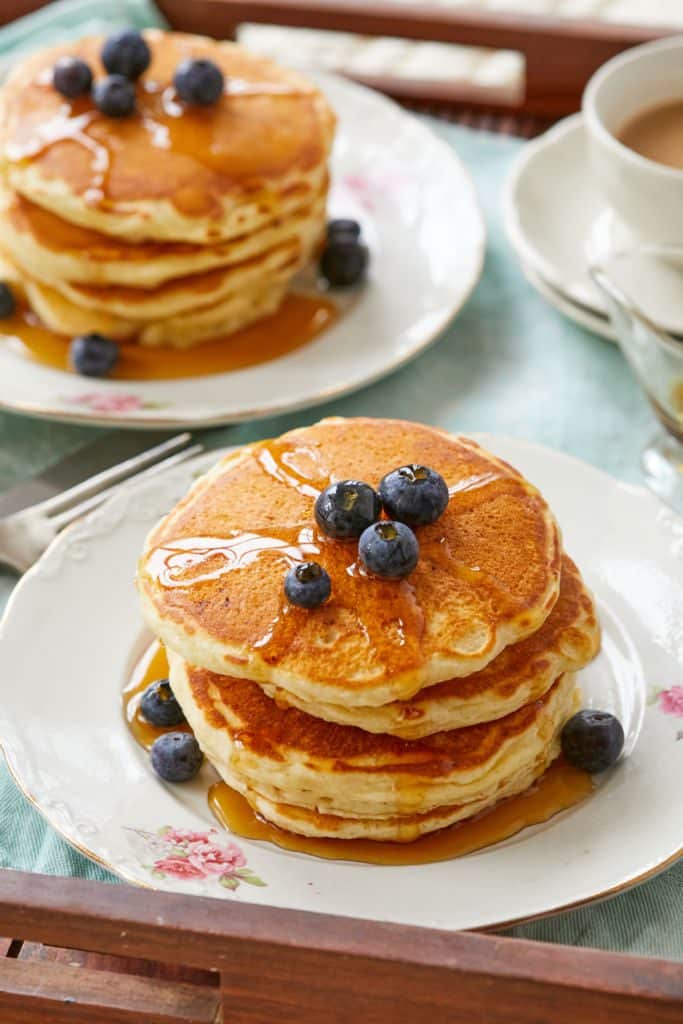 A close up of the pancakes topped with blueberries and syrup.
