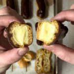 Hands holding a homemade eclair cut in half.
