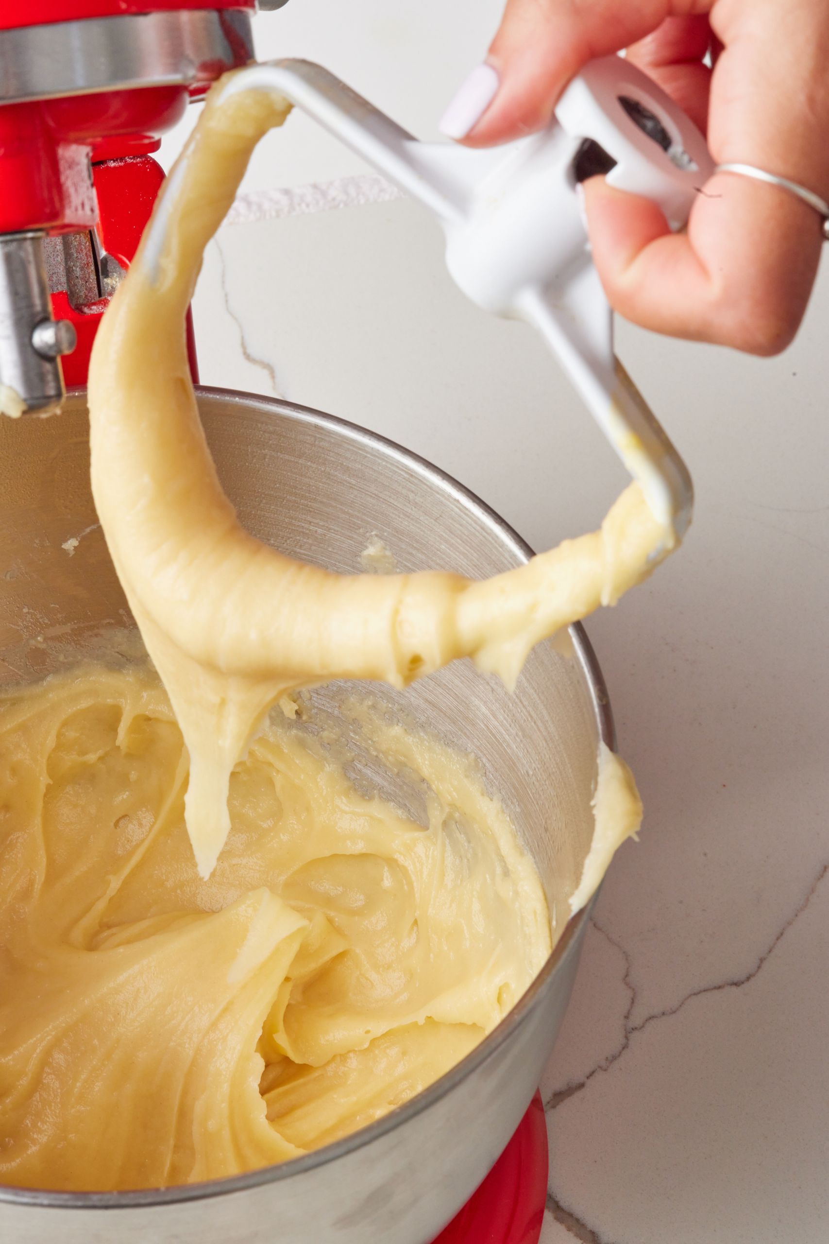 Eclairs6 Toward the end, lift the paddle—your dough should fall slowly and form a “V” shape. If it sticks, add a bit more egg and check again.