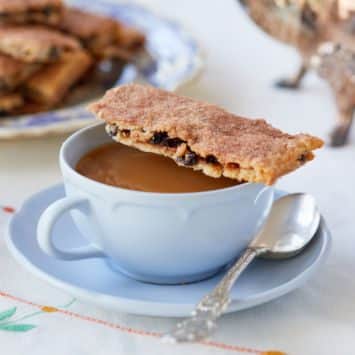 A garibaldi biscuit resting on a cup of tea.