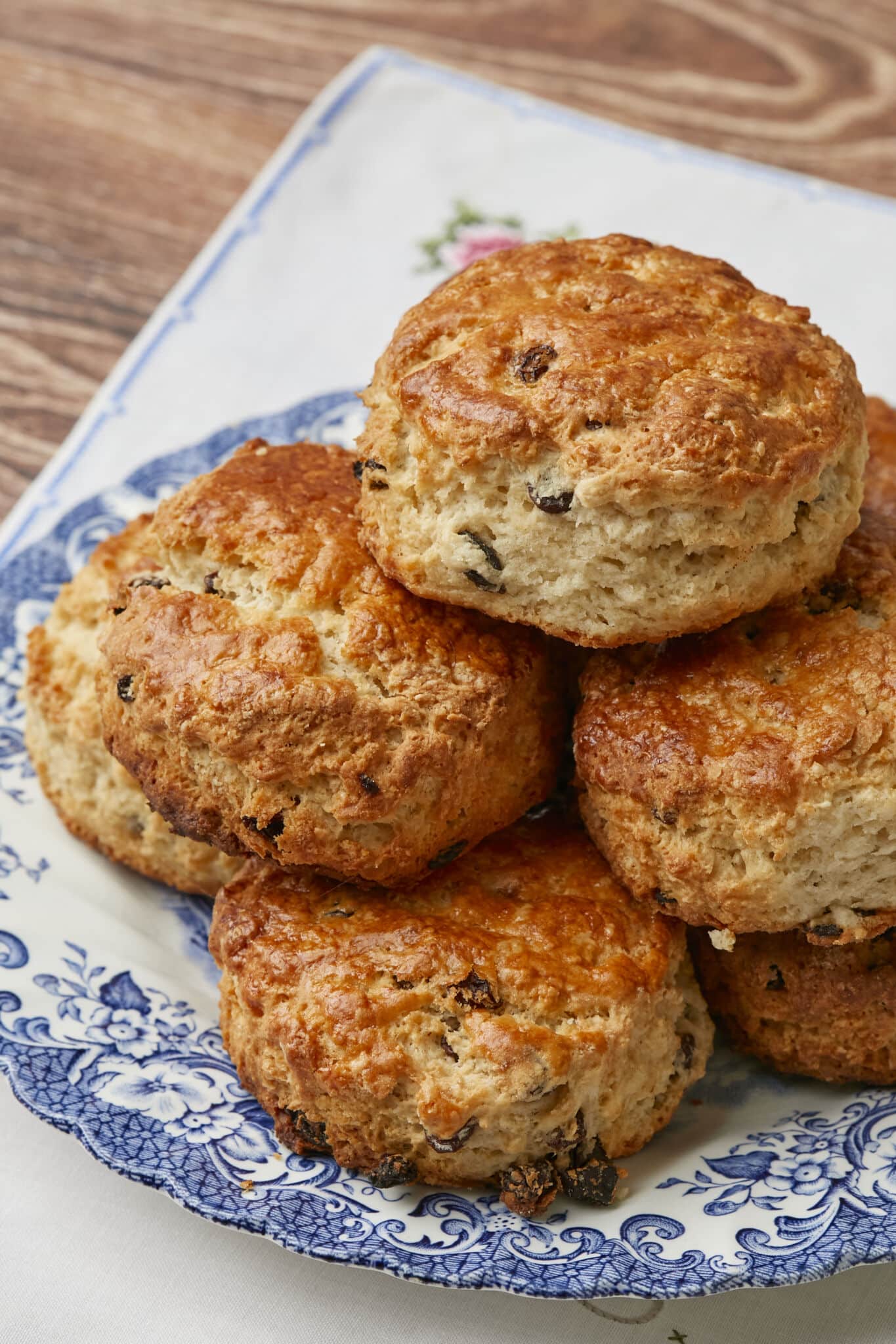 Gemma's Best Ever Irish Scones are served on a floral platter. They are golden brown with a crunchy, crackly exterior and loaded with raisins.
