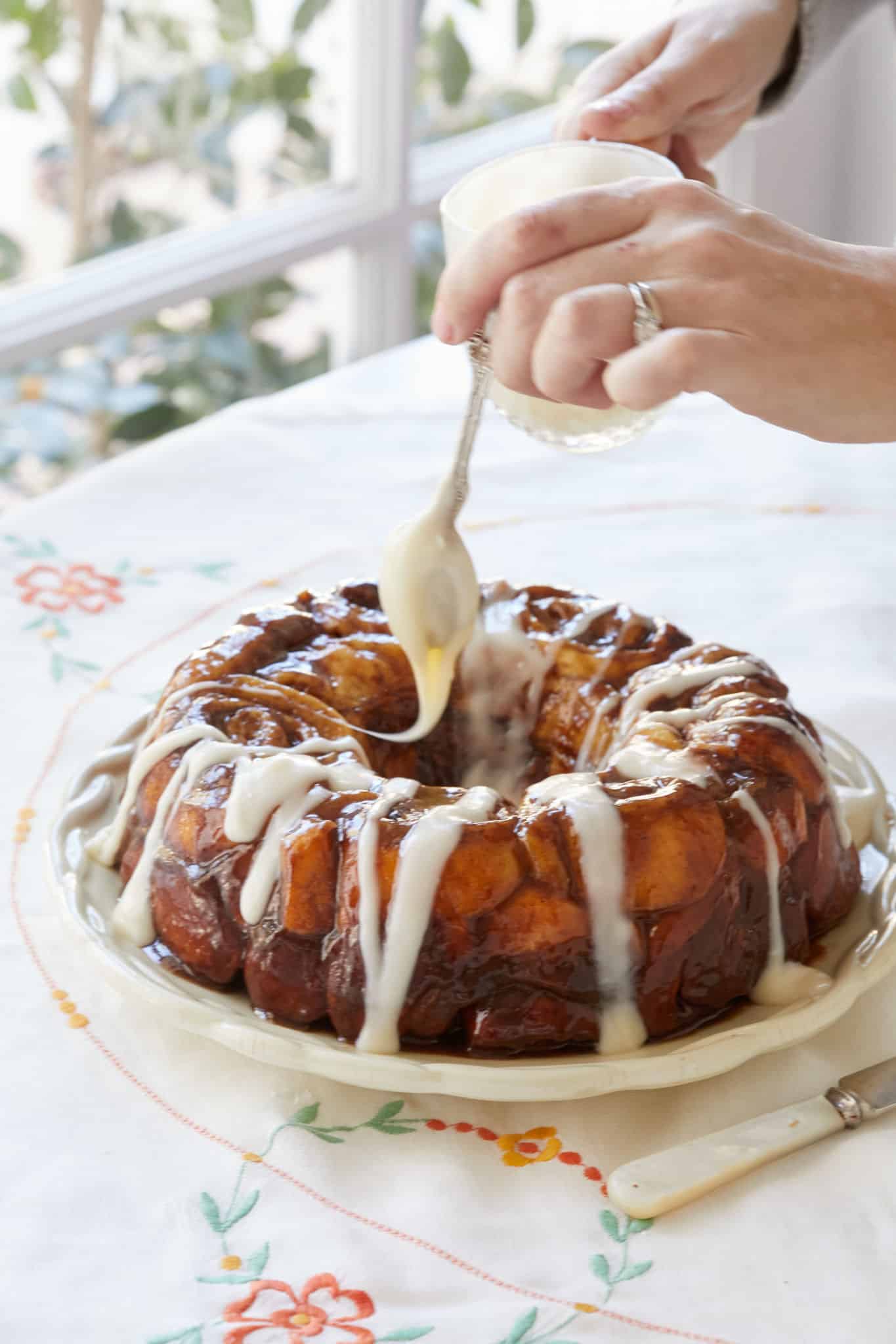 Cinnamon Roll Monkey Bread being drizzled with cream cheese glaze.