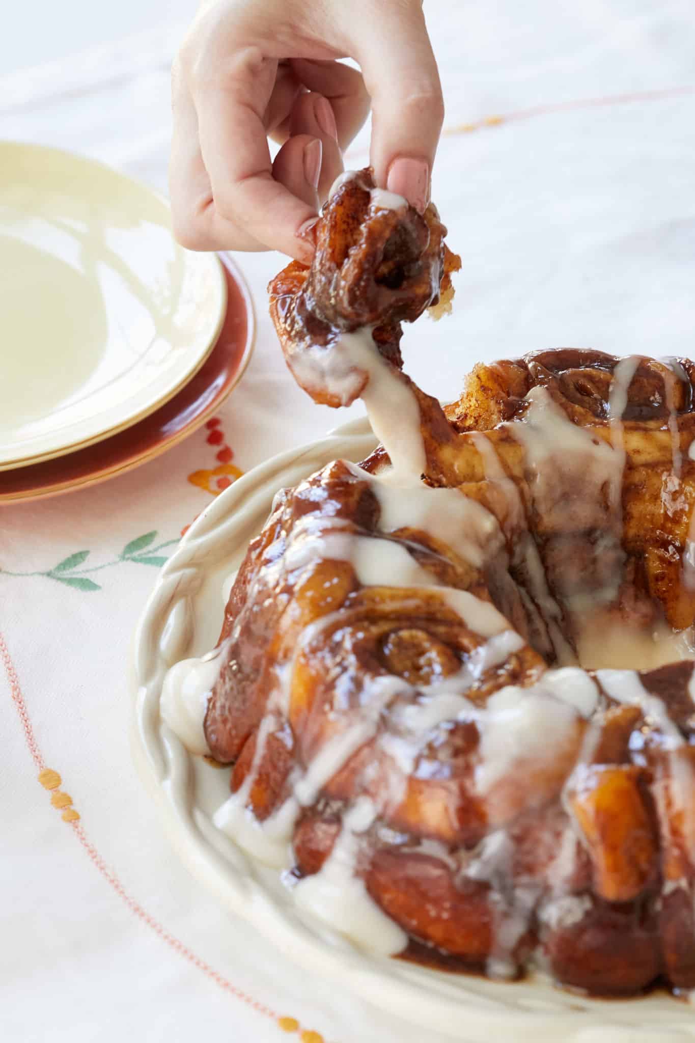 Cinnamon Roll Monkey Bread being pulled apart by a hand.