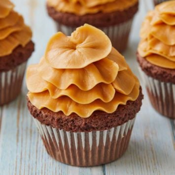 Salted Caramel Swiss Meringue Buttercream on top of four cupcakes.