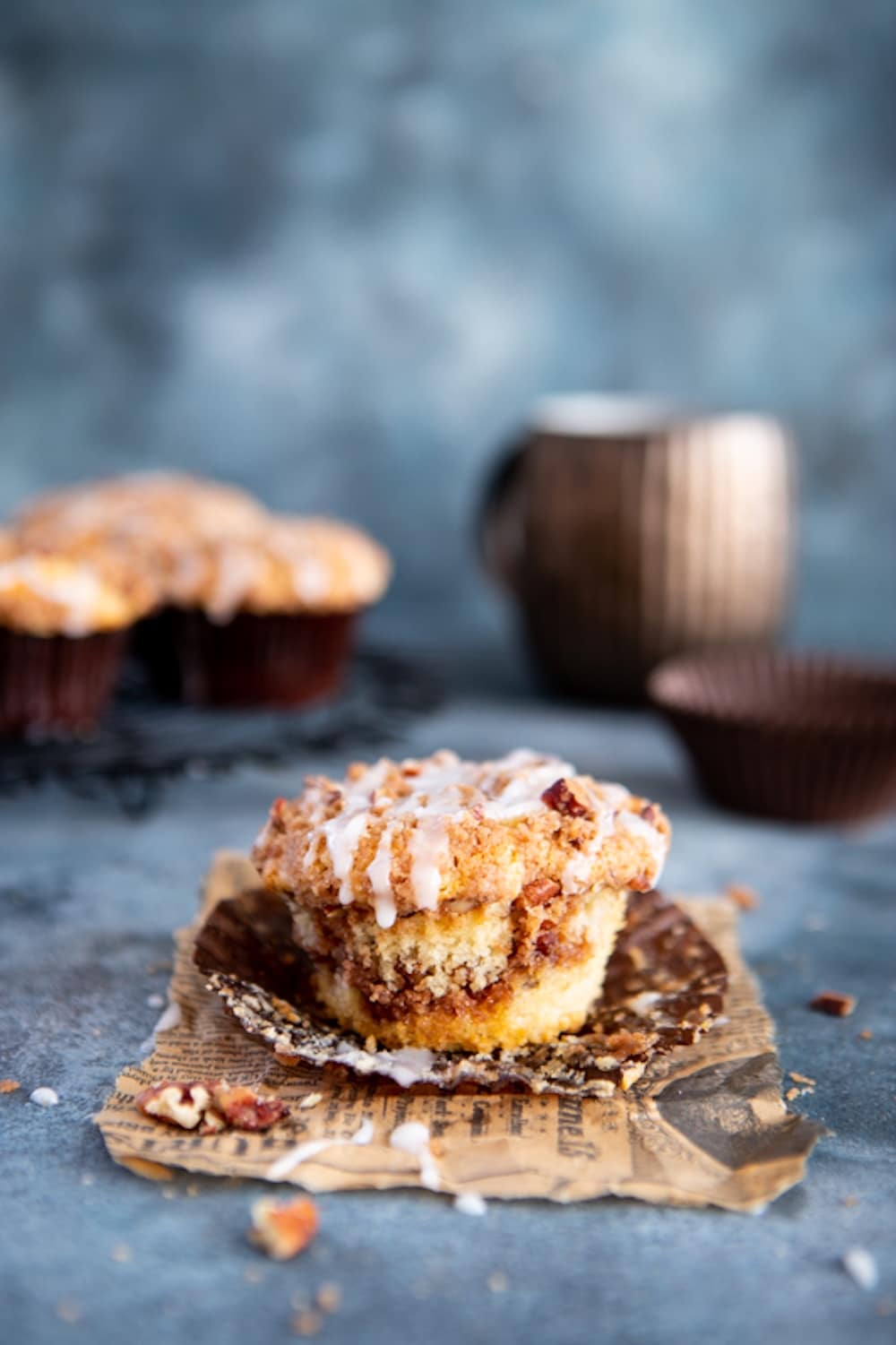 A cinnamon roll muffin with the liner peeled off showing its moist crumb and swirls of cinnamon sugar filling. 