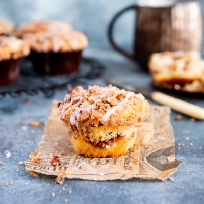 A cinnamon roll muffin with the liner peeled off showing its moist crumb and swirls of cinnamon sugar filling.