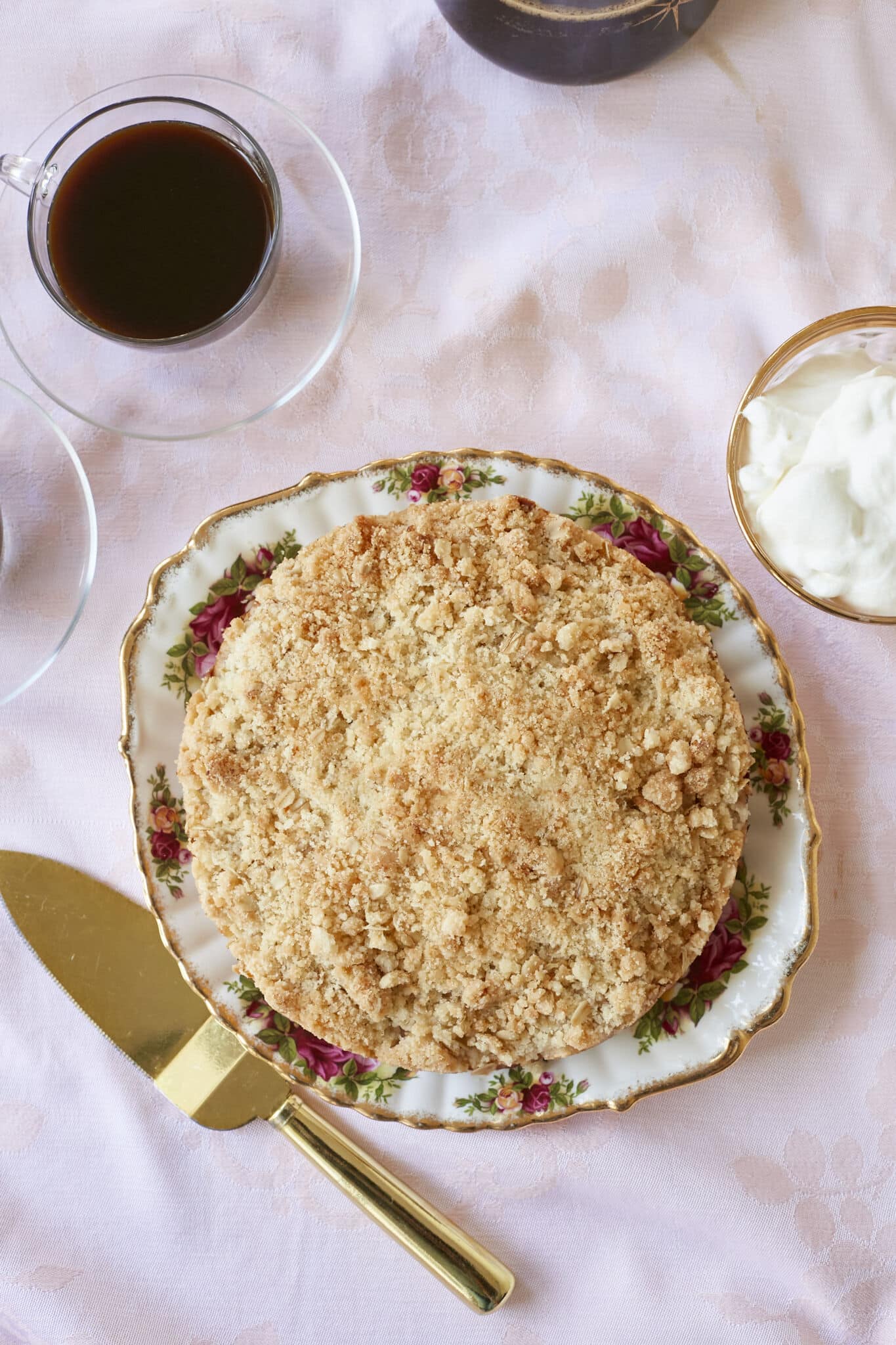 An overhead shot of a golden Irish Apple Cake with coffee and whipped cream on the side. 