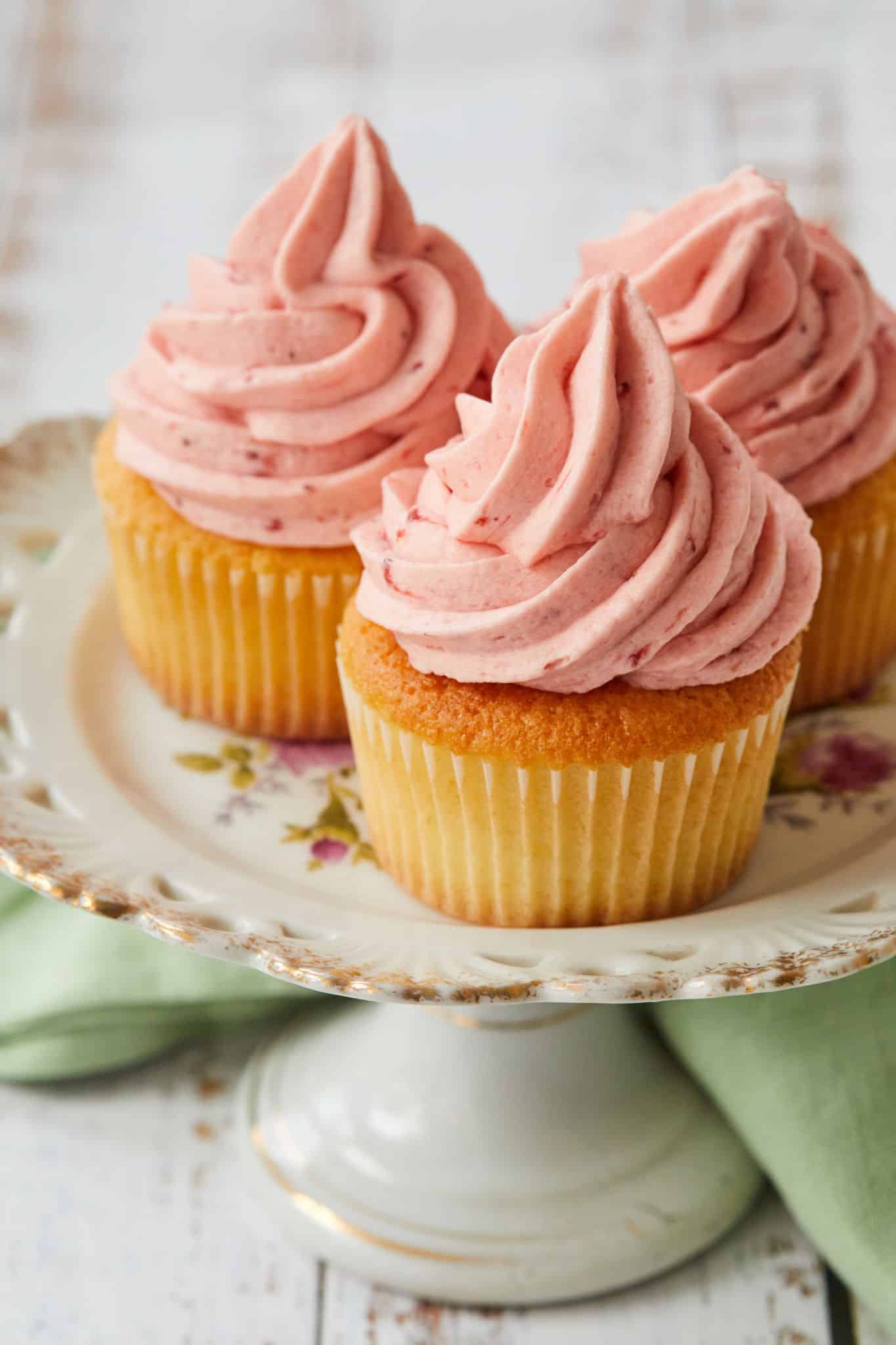 Strawberry Buttercream Frosting twisted high on top of vanilla cupcakes.