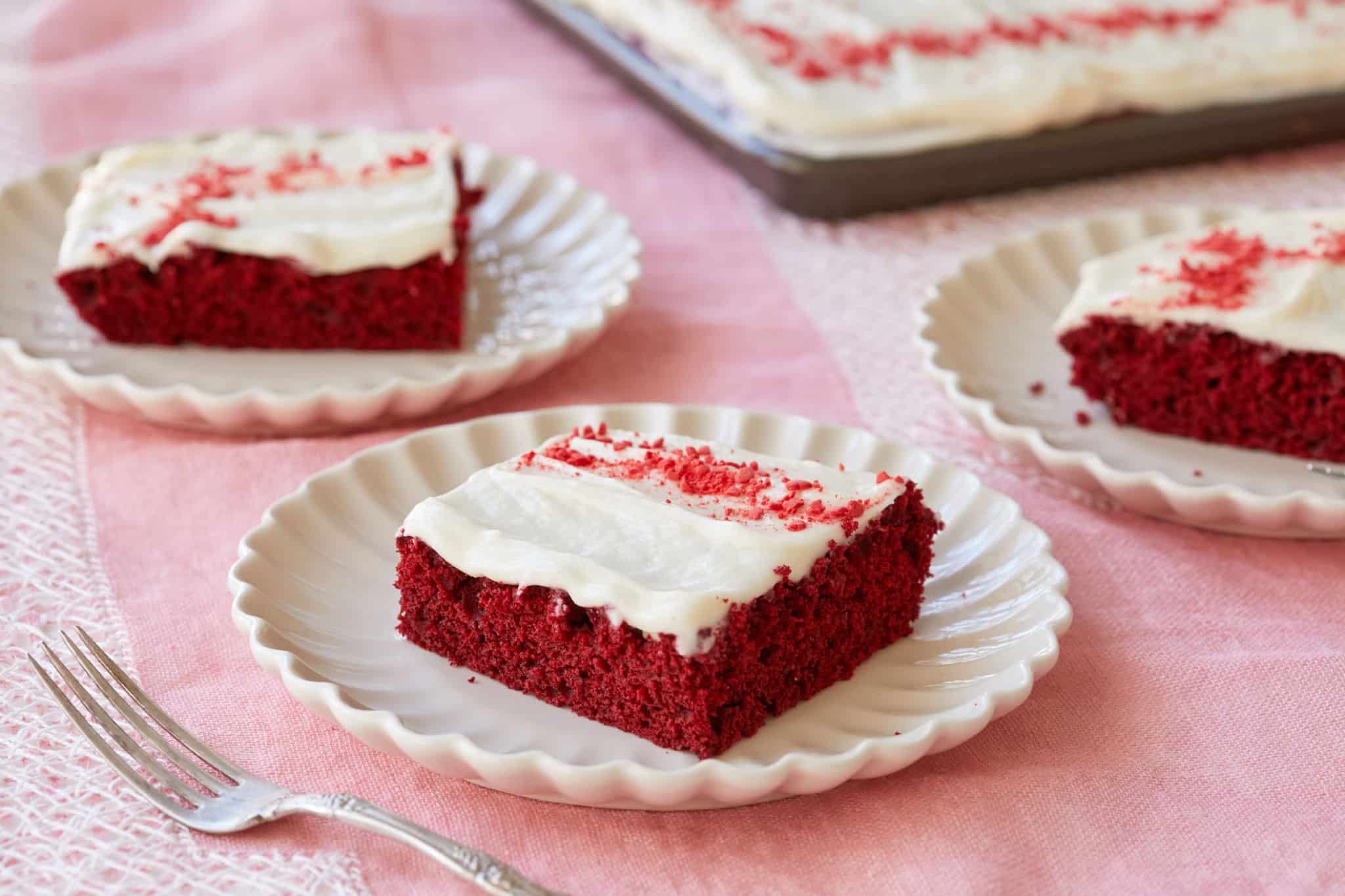 Red velvet sheet cake slices on dishes.
