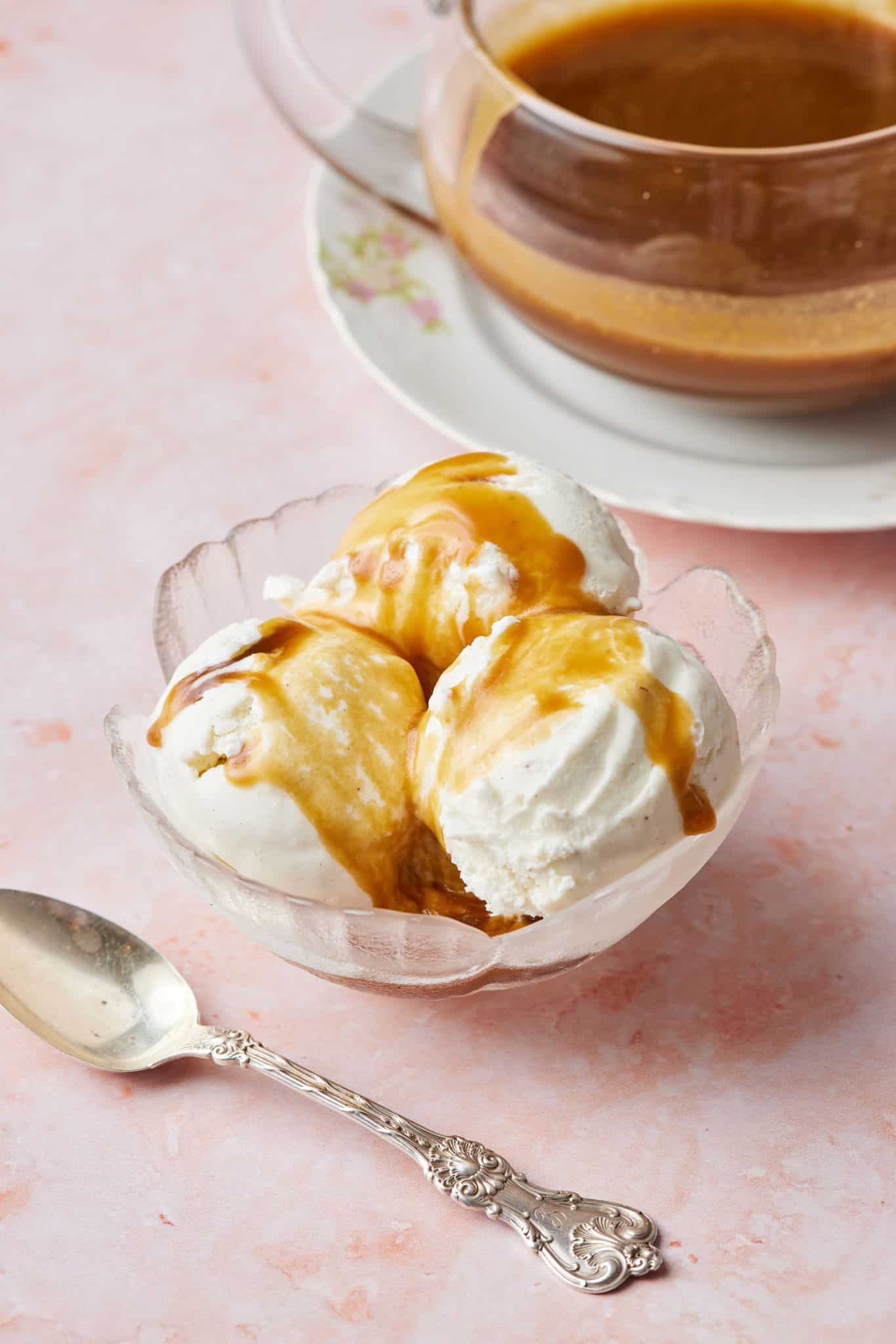Salted caramel sauce drizzled over three scoops of ice cream ,with the jug om the side. 