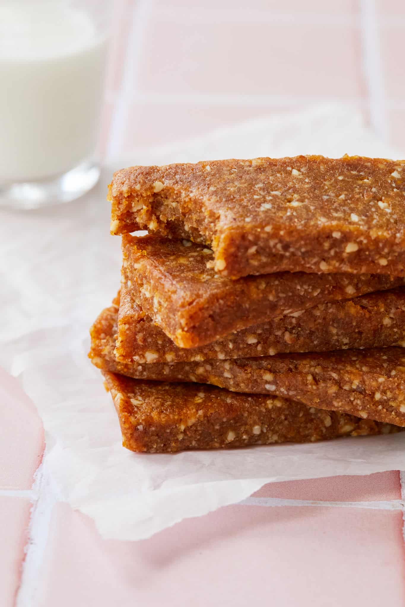 Four homemade Larabars are stacked on each other. These homemade Apricot Almond Larabars are perfect for kid's lunch boxes.