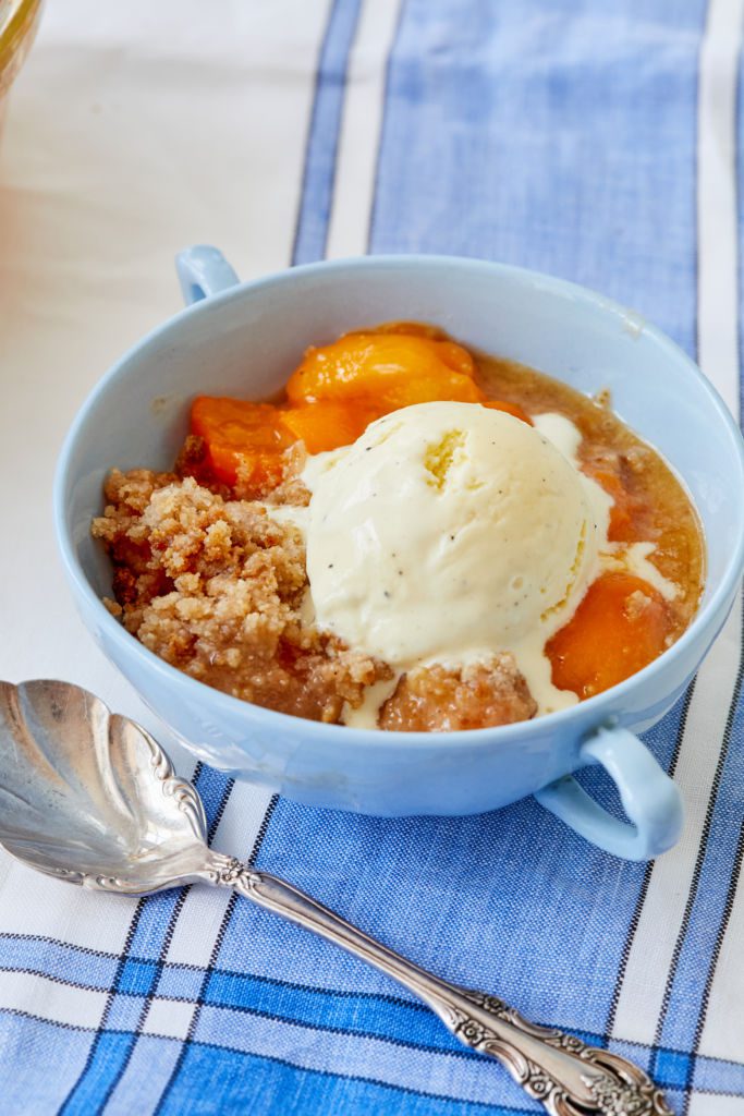 Apricot crumble serving in a bowl topped with vanilla ice cream