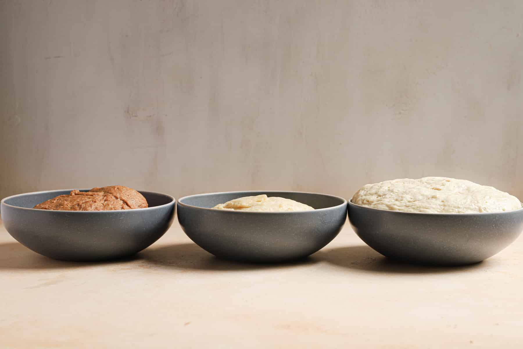 Three bowls with different doughs showing rising height.