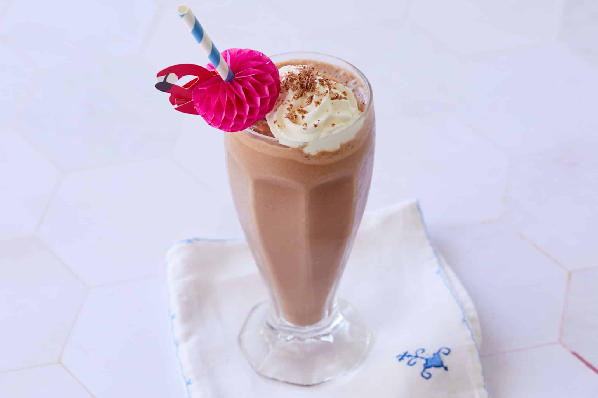 An old-fashioned chocolate malt milkshake, served in a soda fountain inspired glass, with whipped cream.