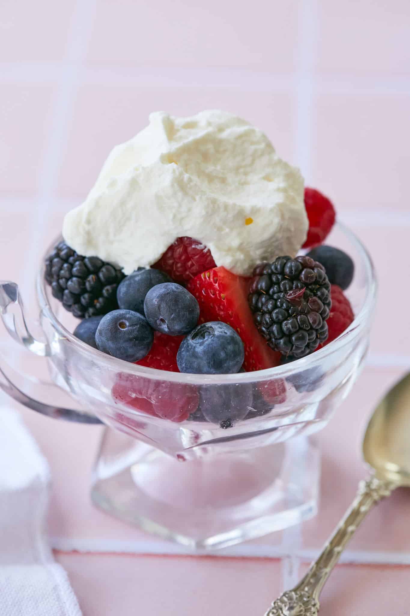A bowl of fresh fruit is topped with a dollop of creme fraiche whipped cream.