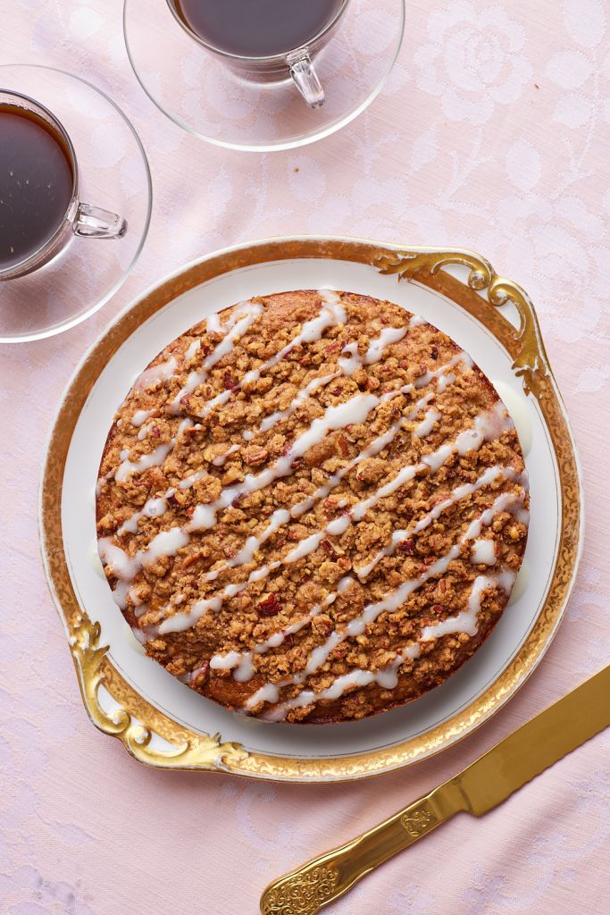 Top down view of hummingbird cake glazed with icing, served with coffee on the side.