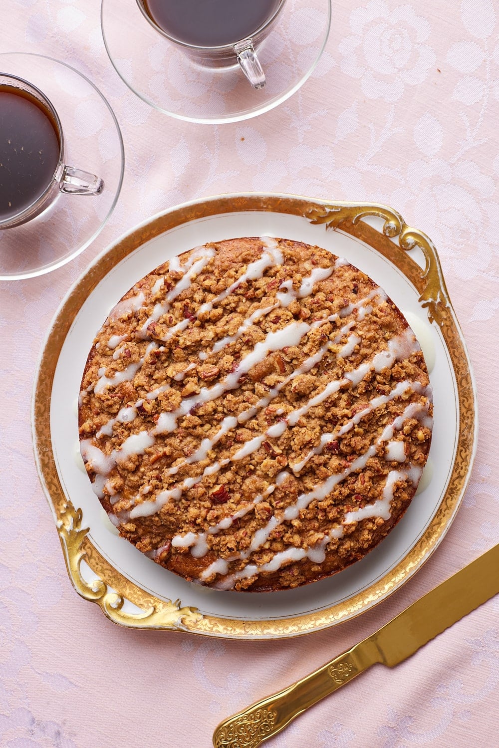 Top down view of hummingbird cake glazed with icing, served with coffee on the side. 