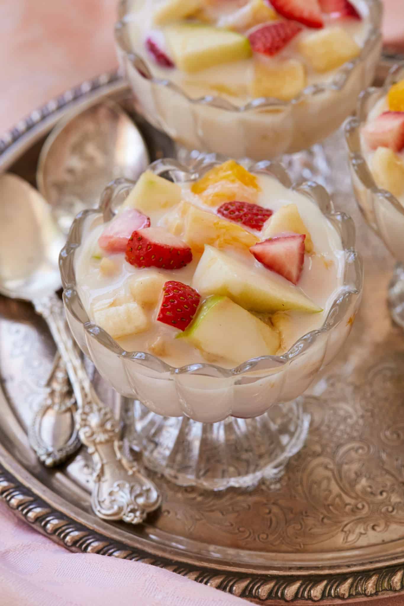Fresh seasonal fruit, including apples, strawberries, and bananas, in a bowl with custard.