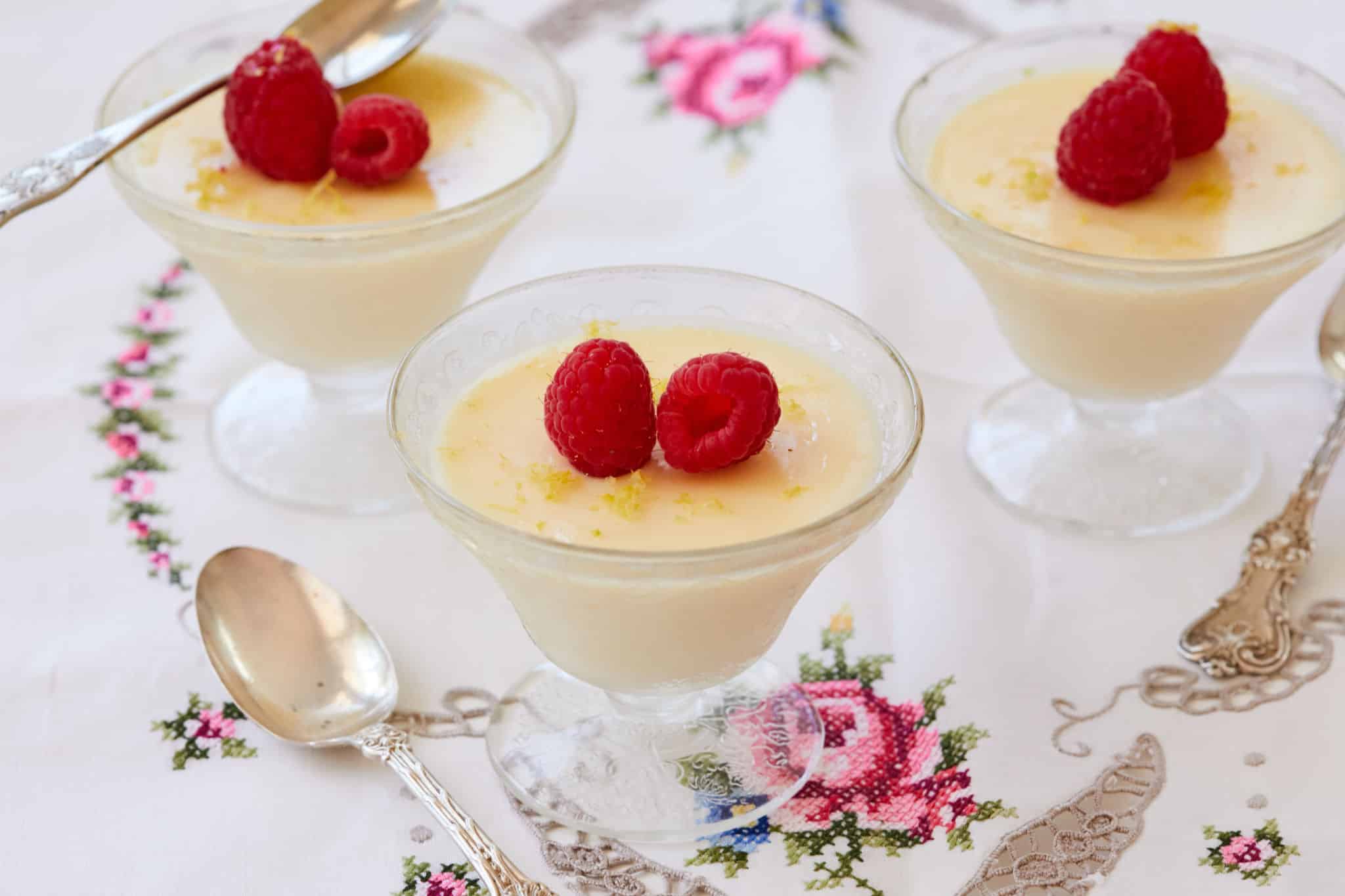 Lemon Posset in elegant dishes topped with raspberries