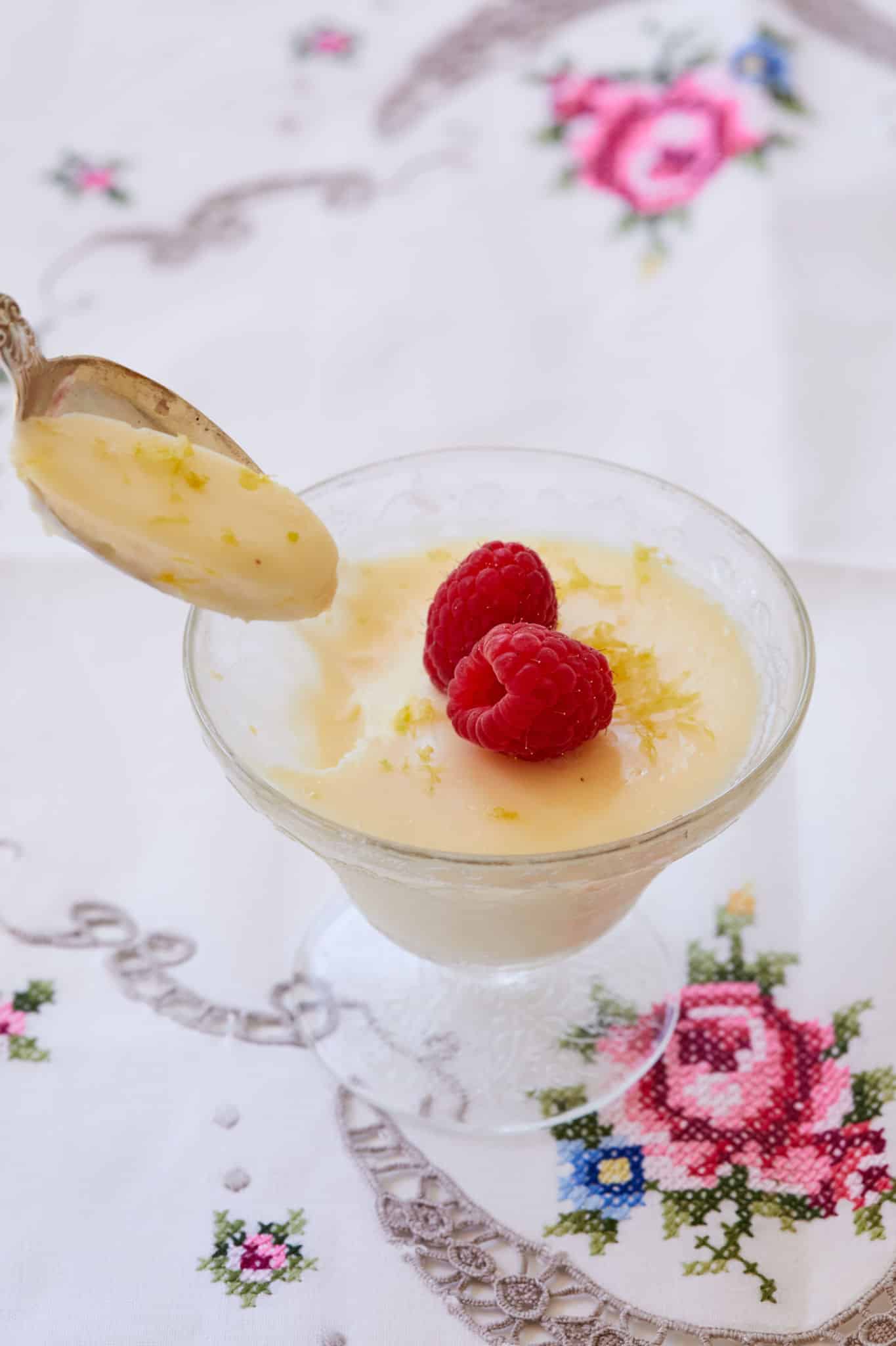 A spoon taking some Lemon Posset out of a dish.