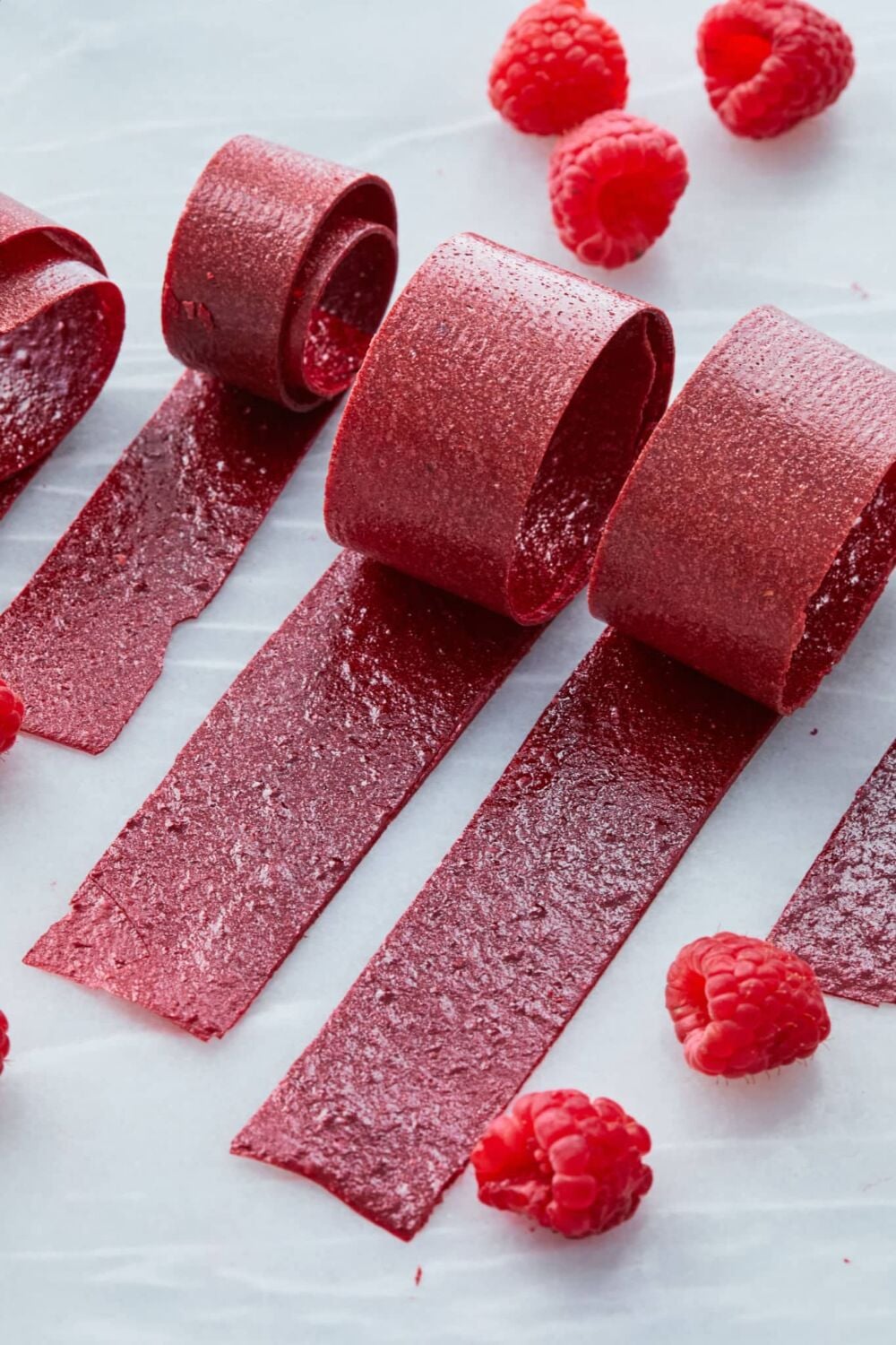 Raspberry Fruit Leather2 Vibrant red Raspberry Fruit rollups with some fresh rasperries.